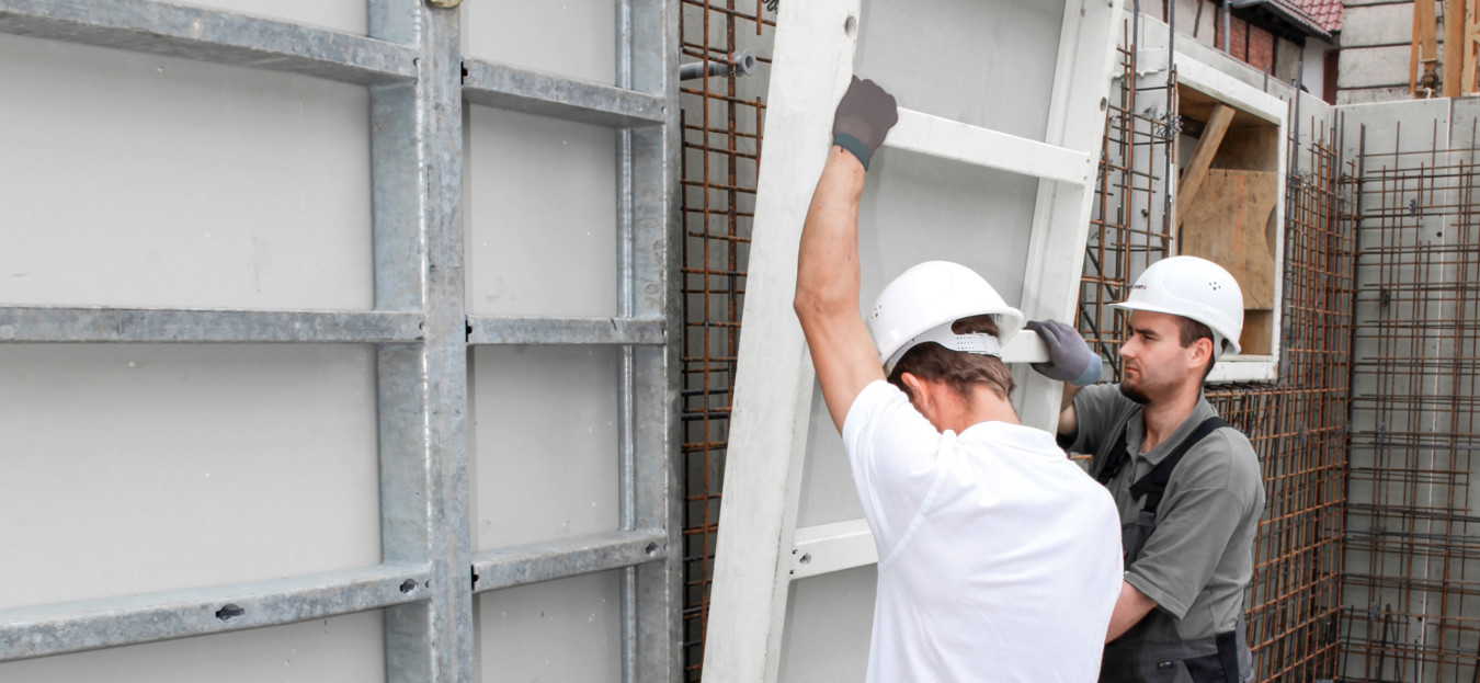 Two men fitting together lightweight formwork panels