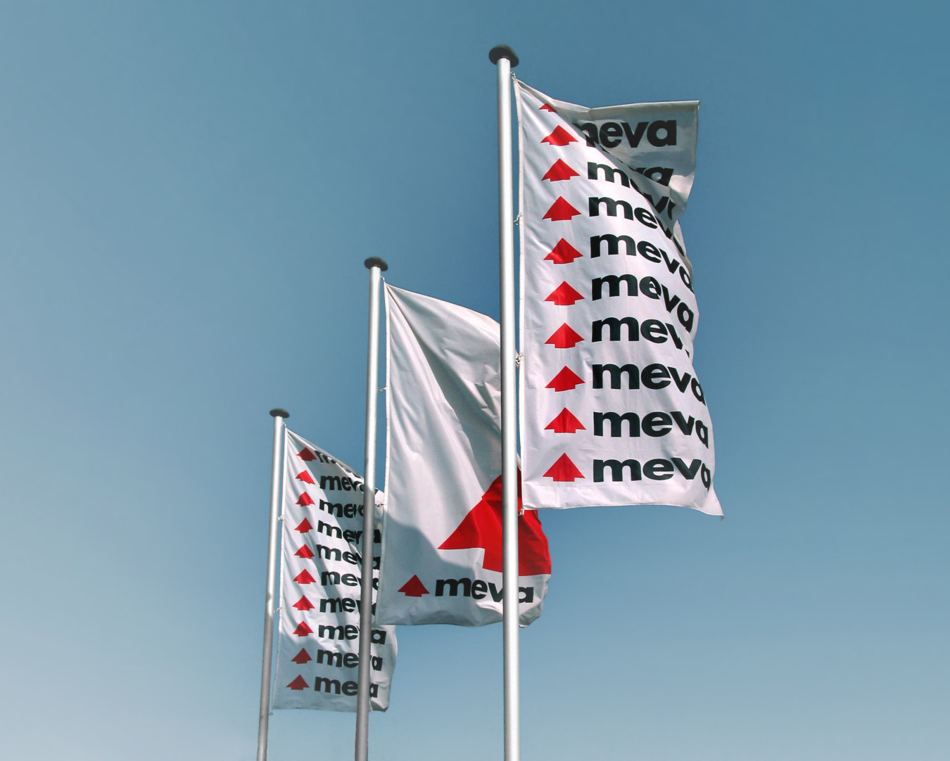Flags showing the MEVA Formwork Systems logo on flags office opening